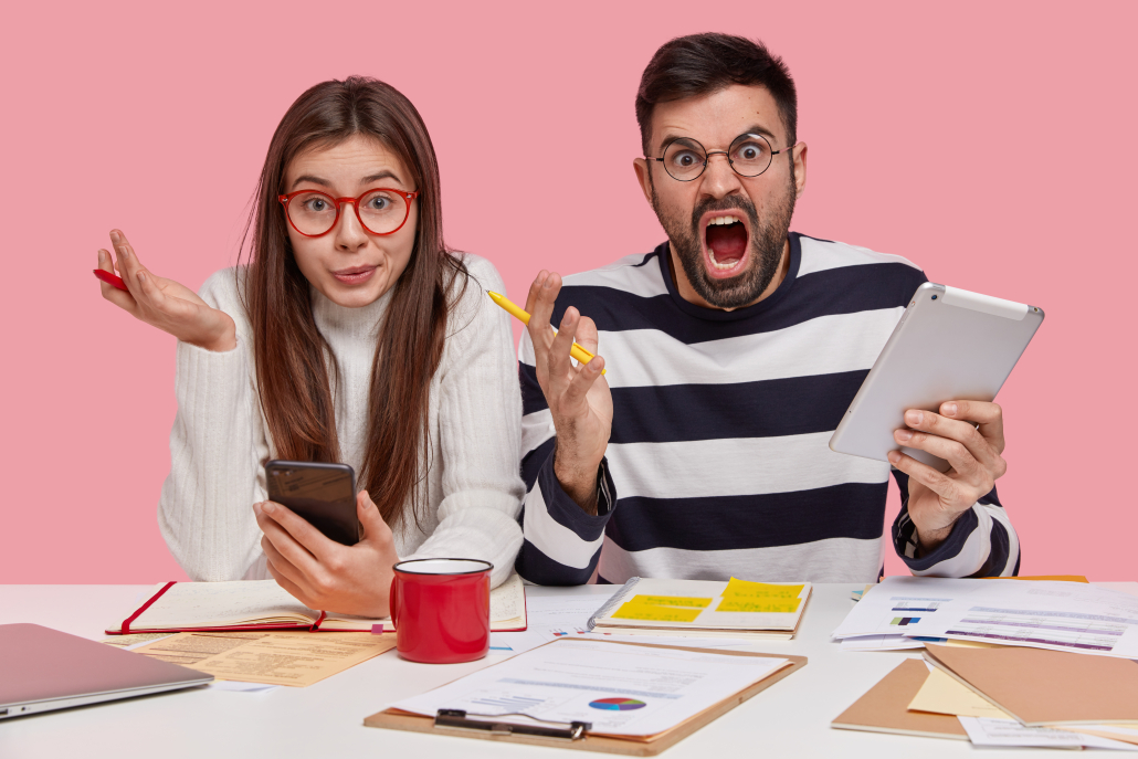Horizontal shot of confused female and annoyed man discuss graphs, work on university project, use modern technologies, do homework together, isolated over pink background. Youth and work concept